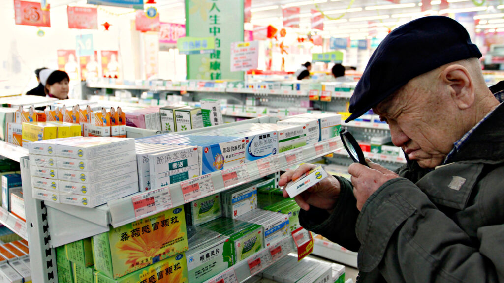 Older man reading a prescription drug label at a pharmacy